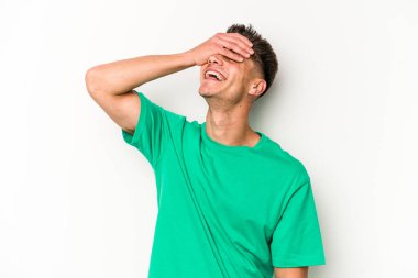 Beyaz arka planda izole olmuş genç beyaz bir adam ellerini başının üstünde tutarak neşeyle gülüyor. Mutluluk kavramı.