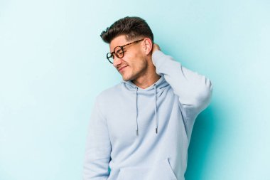 Kafkasyalı genç bir adam mavi arka planda izole edilmiş. Durağan yaşam tarzından dolayı boyun ağrısı çekiyor..