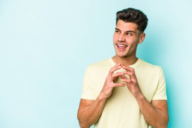 Kafkasyalı genç bir adam mavi arka planda izole edildi. Aklında bir plan kuruyor, bir fikir kuruyor..