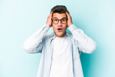 Mavi arka planda izole genç beyaz adam şok oldu, o önemli bir toplantı hatırladı.