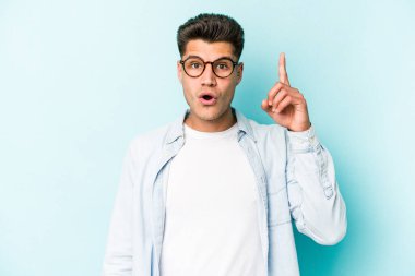 Mavi arka planda izole edilmiş beyaz bir adam ağzı açık bir şekilde üst tarafı işaret ediyor..