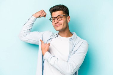 Mavi arka planda izole edilmiş genç beyaz adam güçlü bir hareket sergiliyor kollarıyla, kadınsı gücün sembolü.