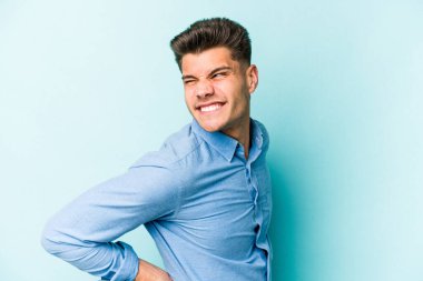 Mavi arka planda izole edilmiş beyaz bir adam sırt ağrısı çekiyor..