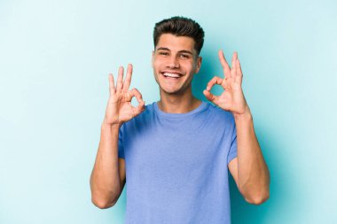 Kafkasyalı genç adam mavi arka planda izole edilmiş neşeli ve kendinden emin..