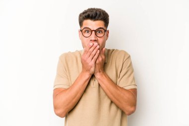 Beyaz arka planda izole edilmiş genç beyaz adam şok olmuş, ağzı ellerle kaplanmış, yeni bir şey keşfetmeye hevesli..