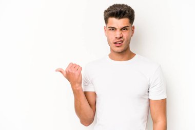 Beyaz arka planda izole edilmiş genç beyaz bir adam işaret parmağıyla fotokopi alanını işaret ederek şok oldu..