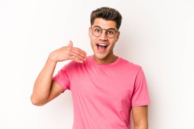 Beyaz arka planda izole olmuş genç beyaz bir adam bir şeye gülüyor, ağızlarını ellerle kapatıyor..