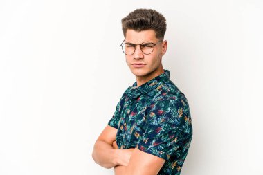 Beyaz arka planda izole edilmiş, hoşnutsuzca kaşlarını çatmış, kollarını kavuşturmuş genç beyaz bir adam..