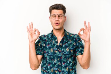 Beyaz arka planda izole edilmiş genç beyaz adam yoğun bir günün ardından rahatlıyor. Yoga yapıyor..