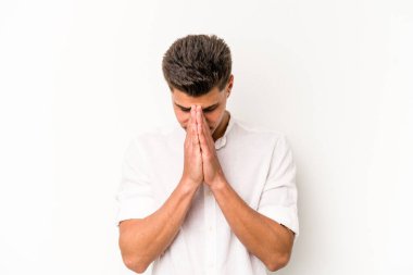 Beyaz arka planda izole edilmiş genç beyaz adam dua ediyor, bağlılık gösteriyor, dindar biri ilahi ilham arıyor..