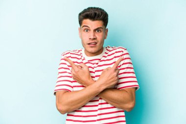 Mavi arka plan noktalarında izole genç beyaz adam, iki seçenek arasında seçim yapmaya çalışıyor.