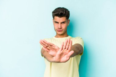 Mavi arka planda izole edilmiş genç beyaz adam elini uzatmış, dur işareti göstererek seni engelliyor..