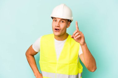 Kafkasyalı genç işçi mavi arka planda izole edilmiş. Bir fikri var, ilham verici bir kavram..