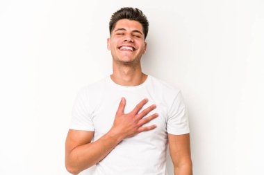 Beyaz arka planda izole genç beyaz adam yüksek sesle gülüyor elini göğsüne koyuyor..