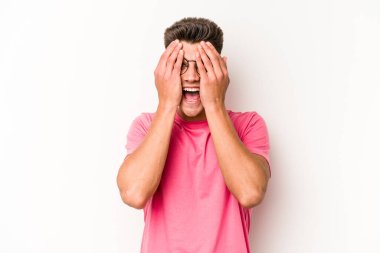 Beyaz arka planda izole edilmiş genç beyaz bir adam yüzünün yarısını palmiye ile örterek eğleniyor..