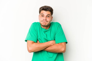 Beyaz arka planda izole edilmiş genç beyaz bir adam omuz silkiyor ve gözleri açık..