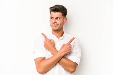Beyaz arka plan noktalarında izole genç beyaz adam, iki seçenek arasında seçim yapmaya çalışıyor.