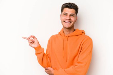 Beyaz arka planda izole edilmiş genç beyaz adam işaret parmağıyla işaret ederek gülümsüyor..