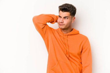 Beyaz arka planda izole edilmiş genç beyaz bir adam kafasının arkasına dokunuyor, düşünüyor ve bir seçim yapıyor..