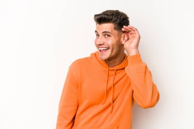 Beyaz arka planda izole edilmiş genç beyaz adam bir dedikoduyu dinlemeye çalışıyor..