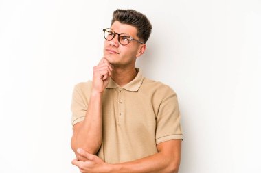 Beyaz arka planda soyutlanmış genç beyaz bir adam düşünüyor ve yukarı bakıyor, yansıtıyor, düşünüyor, hayal kuruyor..