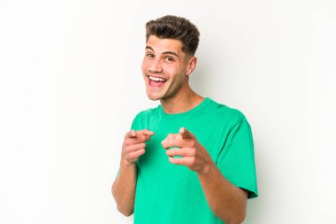 Beyaz arka planda izole edilmiş genç beyaz adam parmaklarıyla ön tarafı işaret ediyor..