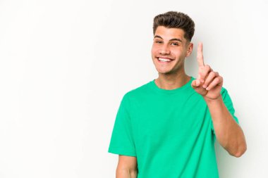 Beyaz arka planda izole edilmiş beyaz tenli genç bir adam bir numarayı parmağıyla gösteriyor..