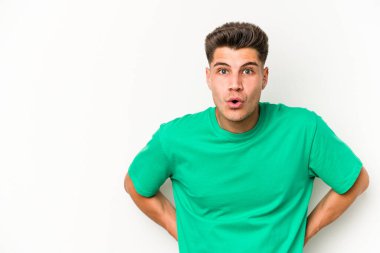 Beyaz arka planda izole edilmiş genç beyaz adam gördüğü bir şey yüzünden şoka uğruyor..