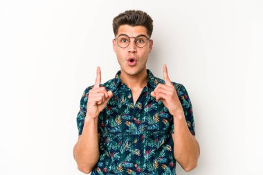 Beyaz arka planda izole edilmiş genç beyaz adam ağzı açık bir şekilde üst tarafı işaret ediyor..