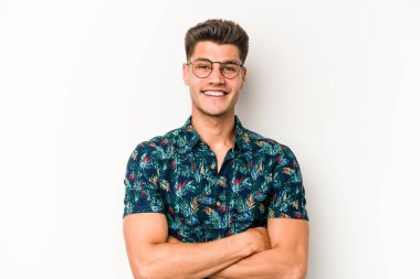 Beyaz arka planda kendini güvende hisseden, kararlılıkla kollarını kavuşturan beyaz tenli genç bir adam..