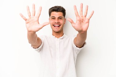 Beyaz arka planda izole edilmiş beyaz tenli genç adam on numarayı elleriyle gösteriyor..