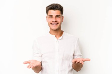 Beyaz arka planda izole genç beyaz adam kollarıyla ölçek yapar, mutlu ve kendinden emin hisseder..