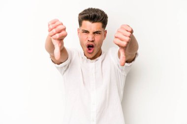 Beyaz arka planda izole edilmiş genç beyaz bir adam baş parmağını aşağı gösteriyor ve hoşlanmadığını ifade ediyor..