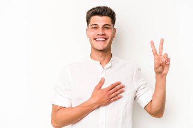Beyaz arka planda izole edilmiş genç beyaz adam yemin ediyor, elini göğsüne koyuyor..