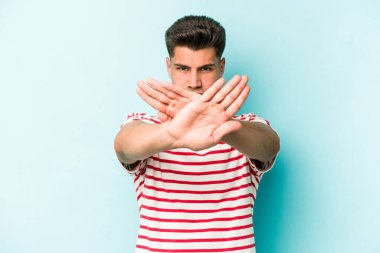 Kafkasyalı genç adam mavi arka planda izole edilmiş bir şekilde inkar hareketi yapıyor.