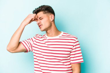 Kafkasyalı genç bir adam mavi arka planda izole edilmiş, başı ağrıyor, yüzüne dokunuyor..