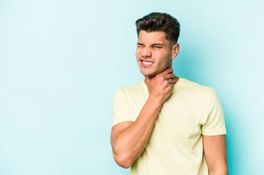 Kafkasyalı genç adam mavi arka planda izole edilmiş kafasının arkasına dokunuyor, düşünüyor ve bir seçim yapıyor..