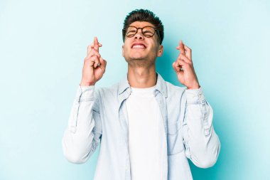 Kafkasyalı genç adam mavi arka planda izole edilmiş şans dilemek için şans diliyor.
