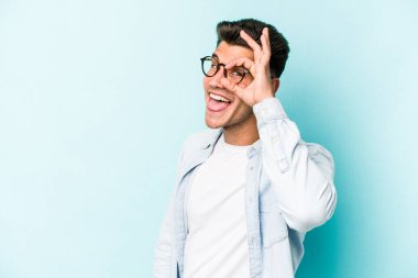 Kafkasyalı genç adam mavi arka planda izole edildi. Heyecanlı görünüyor..