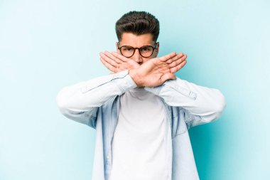 Kafkasyalı genç adam mavi arka planda izole edilmiş bir şekilde inkar hareketi yapıyor.