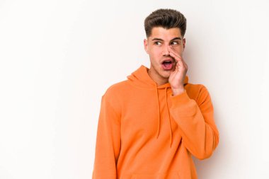 Beyaz arka planda izole edilmiş genç beyaz bir adam gizli bir sıcak fren haberi veriyor ve yana bakıyor.