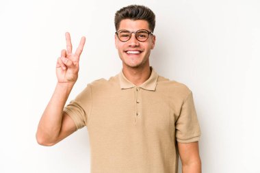 Beyaz arka planda izole edilmiş genç beyaz bir adam neşeli ve kaygısız parmakları olan bir barış sembolü gösteriyor..