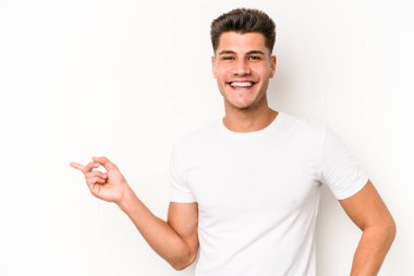 Beyaz arka planda izole edilmiş genç beyaz adam işaret parmağıyla işaret ederek gülümsüyor..
