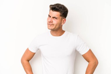 Beyaz arka planda soyutlanmış genç beyaz bir adam kafası karışmış, şüpheli ve güvensiz hissediyor..