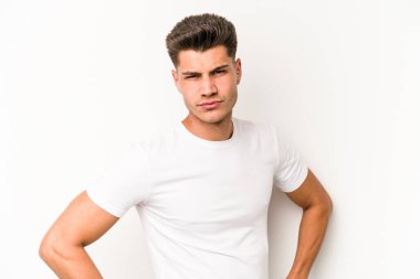 Beyaz arka planda izole edilmiş, hoşnutsuzca kaşlarını çatmış, kollarını kavuşturmuş genç beyaz bir adam..