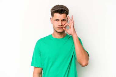 Beyaz arka planda izole edilmiş beyaz tenli genç bir adam parmakları dudaklarında bir sır saklıyor..