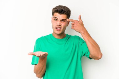 Beyaz arka planda izole edilmiş genç beyaz bir adam elinde bir ürün tutuyor ve.