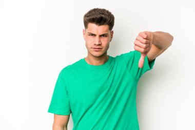 Beyaz arka planda izole edilmiş genç beyaz bir adam baş parmağını aşağı gösteriyor ve hoşlanmadığını ifade ediyor..