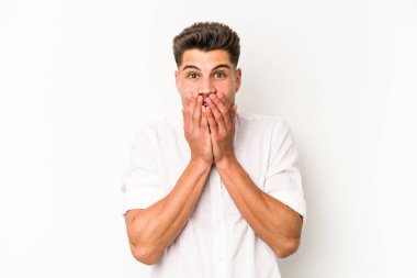 Beyaz arka planda izole edilmiş genç beyaz adam şok olmuş, ağzı ellerle kaplanmış, yeni bir şey keşfetmeye hevesli..