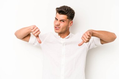 Beyaz arka planda izole edilmiş genç beyaz adam baş parmağını aşağı gösteriyor, hayal kırıklığı konsepti..